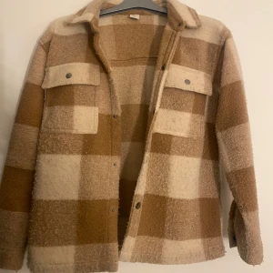 Rutig teddyjacka från Lindex - Säljer en sjukt mysig teddyjacka från Lindex i storlek 158/164. Jackan är använd, och saknar en knapp på ena fickan framifrån men det syns inte🤗🤗