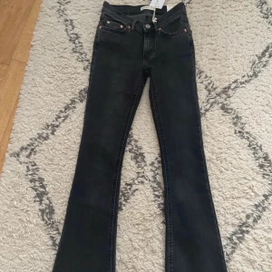 Bootcut jeans i offblack, storlek 32 - Snygga bootcut jeans i offblack med låg midja och klassisk femficksdesign. Jeansen har en stilren look och är tillverkade i jeansmaterial med lätt stretch. Passar dig som gillar en avslappnad men trendig siluett med lite utsvängda ben.