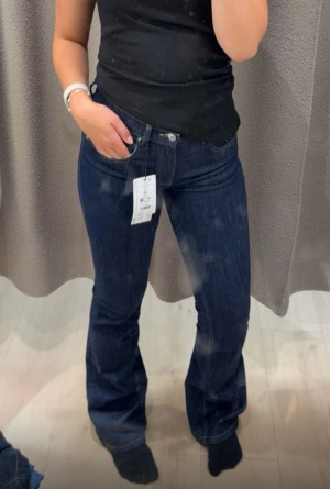 Mörkblå bootcut jeans från Gina Tricot. - Snygga mörkblå jeans från Gina Tricot med klassisk bootcut passform. Jeansen har fem fickor, knapp och dragkedja framtill samt en stilren look som passar till många olika stilar. Materialet är slitstarkt jeans och midjan är normal.