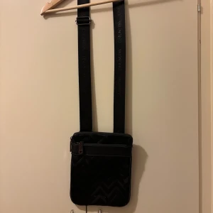  Valentino axelremsväska  - Snygg svart axelväska från Valentino med bred justerbar rem. Väskan har dragkedja upptill och extra fack både fram och bak.