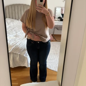 True Religion Joey flare jeans blå - Säljer ett par mörkblå True Religion Joey jeans med låg midja och flare-ben. De är bara använda 3-4 gånger. Jeansen är också uppsydda och är därför kortare men passar bra för mig som är 161 cm,  i kan se på bild 3 hur de ser ut. 