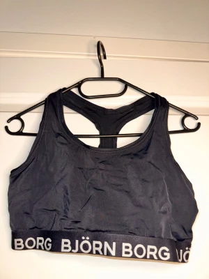 Svart sporttopp från Björn Borg - Sportig svart linnetopp från Björn Borg med brottarrygg och bred resår med logga runt om. Tillverkad i funktionsmaterialet Hydro-Pro som andas och passar perfekt för träning. Snygg och enkel design med stilren look.