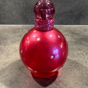 Fantasy Eau de Parfum 100ml - Fantasy Eau de Parfum 100ml från Britney Spears. En ikonisk parfym i en glittrande rosa flaska, perfekt för dig som vill sticka ut. Använd några fåtal gånger, därför är det mycket parfym kvar☺️
