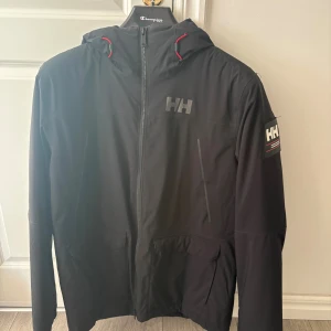 Svart jacka från Helly Hansen - Svart jacka från Helly Hansen med luva. Jackan är i mycket bra skick, nypris 2500 kr. Skriv vid frågor!! 