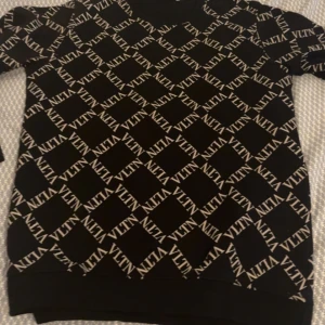 Svart tröja med mönster från Valentino - Svart  tröja från valentino med valentino loggan runt hela tröjan. Nästan helt nytt skick. Passar folk med storlek M och S