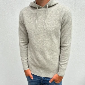 Ljusgrå Kashmir hoodie med huva - Mysig ljusgrå  Kashmir hoodie med huva och snörning. Tröjan har lång ärm och ribbade muddar vid ärmslut och nederkant. Perfekt för kyliga dagar och enkel att matcha med jeans eller andra byxor.