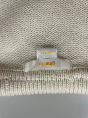 Randig stickad tröja från Gina Tricot - Säljer en vit stickad tröja från Gina Tricot med svarta horisontella ränder. Tröjan har en bred krage, v-ringning och långa ärmar. Modellen är lite loose och har ribbade muddar vid ärmslut och nederkant.