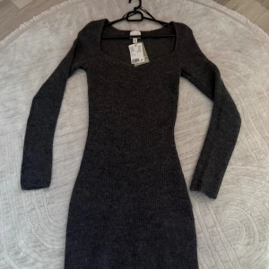 Mörkgrå ribbad klänning H&M XS - Snygg mörkgrå ribbad klänning från H&M i storlek XS. Klänningen har lång ärm, figurnära passform och en djup, fyrkantig ringning. Perfekt för dig som gillar stilrena och enkla plagg med en modern touch.