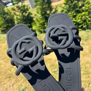 Svarta sandaler  - Säljer ett par svarta sandaler med ikonisk GG-logo framtill. De har fyrkantig tå och platt sula, tillverkade i syntetmaterial. Använda en gång. Storlek 40 men passar mer 39.😊🫶🏻