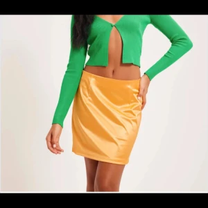 Gul satin minikjol  - Snygg gul minikjol från NELLY i glansigt satinmaterial. Kjolen har en rak passform med liten slits fram för extra edge. Perfekt att styla med crop tops eller stickade tröjor för en trendig look. Färgen är riktigt poppig och materialet känns lyxigt. Aldrig använd med prislapp kvar 