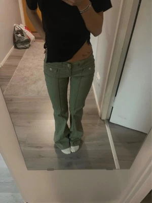Gröna lågmidjade bootcut byxor - Populära och snygga gröna byxor från h&m med låg midja och bootcut-snitt. Byxorna har två framfickor med knappar☺️Som nya, använda kanske två gånger. Klippta så de passar runt 160. 