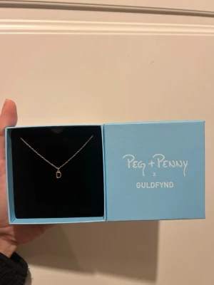 Guldpläterat halsband med ett D - Guldpläterat halsband med bokstaven D från Peg och Penny Parneviks kollektion. I originalförpackning och aldrig använd. 