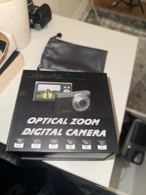 Dacota Platinum Optical Zoom Digital Camera - Dacota Platinum digitalkamera med 16MP, 1080p video, 3x optisk zoom, 5x digital zoom, ansiktsigenkänning och anti-skak. Levereras med batteri, minneskort och skyddspåse. Kameran är i gott skick och fungerar utmärkt.