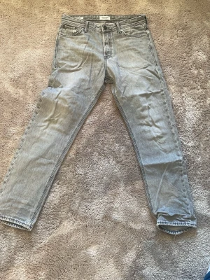 Grå loose fit jeans från Jack & Jones - Snygga grå jeans från Jack & Jones med loose fit-modell 'Chris'. Klassisk femficksdesign, raka ben och tydliga sömmar. Jeansen har en cool tvättad look och är tillverkade i slitstarkt bomullsmaterial. Perfekt för dig som gillar avslappnad stil.