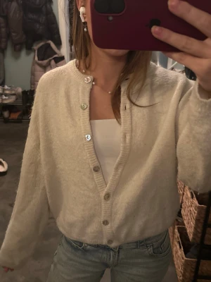 Krämvit kofta från Gina Tricot XS - Mysig krämvit kofta från Gina Tricot i storlek XS. Koftan har långa ärmar, ribbad kant och knappar framtill. Materialet är mjukt och stickat, perfekt för lager-på-lager. Enkel och stilren design som funkar till jeans eller kjol.