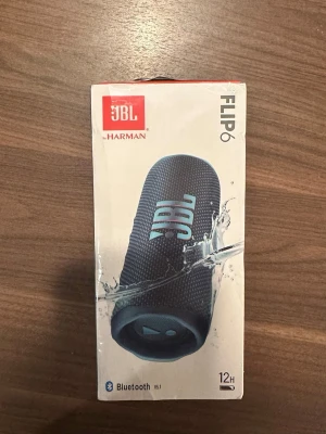 JBL Flip 6 - JBL Flip 6 bärbar Bluetooth-högtalare med kraftfullt ljud, 12 timmars batteritid och IP67-klassning för vatten- och dammtålighet. Stöder PartyBoost för att koppla flera högtalare. Förpackningen är oöppnad men har mindre skavanker.