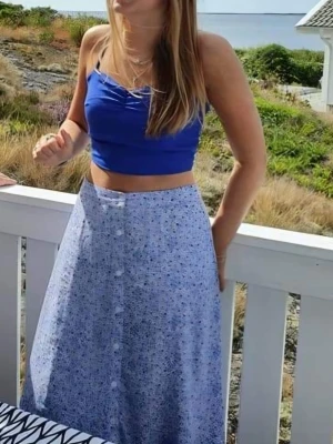 Blå croppad linnetopp från BikBok - Säljer en blå croppad linnetopp från BikBok i storlek XS. Toppen har smala axelband, rynkad smock på ryggen och en snygg rynkdetalj framtill. Perfekt för varma dagar och enkel att matcha med jeans eller kjol.