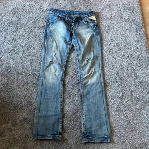 Replay ljusblå jeans, midwaist, 27/32 - Säljer ett par ljusblå jeans från Replay med slitningar och snyggt tvättad look. Säljer pga att jag inte använder dem, men är i väldigt bra skick 