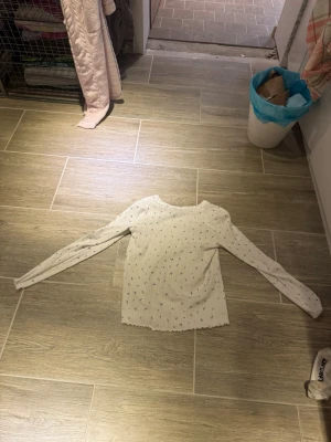 Vit blommig långärmad topp XS - Säljer en söt vit långärmad topp från C i storlek XS. Toppen har små lila blommor som mönster och är ribbad med diskreta hålstickade detaljer. Materialet känns mjukt och stretchigt, perfekt för dig som gillar romantisk stil.