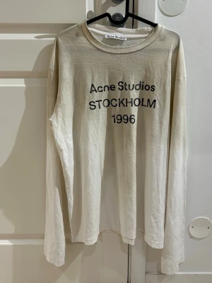 Dusty white långärmad topp Acne Studios S - Säljer en Dusty White långärmad topp från Acne Studios med svart tryck 'Acne Studios STOCKHOLM 1996' på framsidan. Rund halsringning med distressing och dusty effect och loose passform. Den är ny och oanvänd har bara testat den. Fraktas 24timmar efter köp.