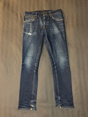 Nudie jeans grim tim slim fit dry - Tja säljer ett par nudie jeans med riktigt sjul wash. Storlek W30 L30, modellen heter Grim tim och den sitter slim. Har en lagning i skrevet som visas på sista bilden