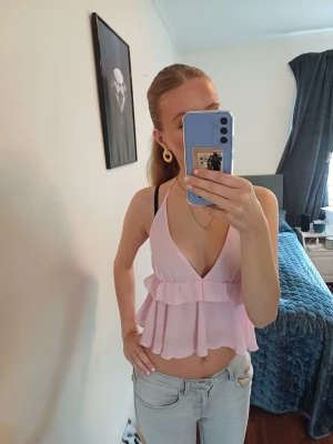 Ljusrosa volang topp med djup v-ringning - Säljer en hjäte söt ljusrosa topp med volangdetaljer och djup v-ringning. Toppen knyter man bak I naken och har tunna axelband. Perfekt för fest eller sommaren ❤️ skriv för mer frågor 