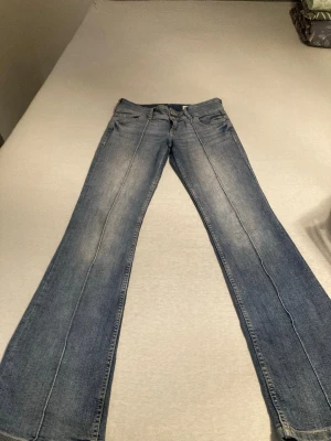 Blå bootcut jeans från Bershka - Säljer ett par snygga blå jeans från Bershka i bootcut-modell. Jeansen har klassisk femficksdesign, ljus tvätt och raka ben som blir bredare nedtill. Materialet är jeans och de har normal passform. Perfekta för dig som gillar retrovibbar och vill ha ett coolt statement-plagg.