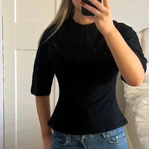 Svart figurnära topp med halvlånga ärmar - Fin t-shirt med figurnära passform med lite luftigare armar. Aldrig använd med prislapp kvar.