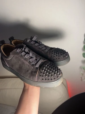 Christian Louboutin  - Svarta sneakers från Christian Louboutin med klassisk röd sula och coola nitar på tån. Skorna är gjorda i mocka och har snörning samt rund tå. Insidan är beige och sulan har Louboutin-loggan. Perfekt för dig som gillar edgy och lyxig stil. Hör av er vid funderingar🙌 bara skor ingen box eller dustbag medföljer. Mvh Melwin🙌