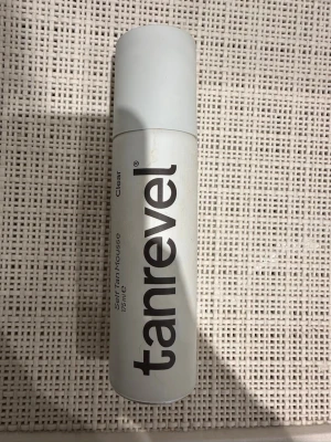 Tanrevel Self Tan Mousse Clear 175ml - Tanrevel Self Tan Mousse Clear är en transparent brun-utan-sol mousse som ger en naturlig solkysst ton på 3-6 timmar. Passar alla hudtoner och har en lätt, doftfri formula. Flaskan är vit med svart text och rymmer 175 ml mousse.