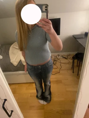 Ribbad stickad topp - Snygg blå stickad tröja med ribbad struktur och korta ärmar. Tröjan har en rundad halsringning och är croppad i modellen, vilket ger en modern och fräsch look.