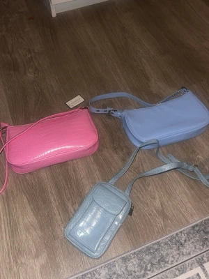 Pastellfärgade handväskor i crocopräglat - Tre trendiga handväskor i pastellfärger: en rosa och en ljusblå axelremsväska samt en mindre ljusblå crossbody-väska. Alla väskor är nya och säljer alla för endast 317!