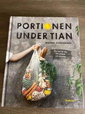 Portionen under tian av Hanna Olvenmark - En inspirerande kokbok med över 50 vegetariska recept som kostar max tio kronor per portion. Väldigt bra skick, nästintill aldrig använd. 