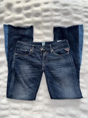 Mörkblå bootcut jeans med låg midja Replay - Snygga vintage mörkblå bootcut jeans från Replay med låg midja och klassiska fem fickor. Jeansen har slitna detaljer. Har sytt om de själv med symaskin från straight leg till bootcut och även sytt mer lågmidjat (se bilder).  Storlek 27 waist 32 lenght. Säljer pga för små. Passar 26 också