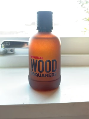 DSQUARED2 Wood Original parfym 100ml - Säljer en DSQUARED2 Wood Original parfym i en snygg brun frostad glasflaska med svart lock. Flaskan har en stilren och modern design med tydlig logga framtill. Perfekt för dig som gillar träiga och maskulina dofter.