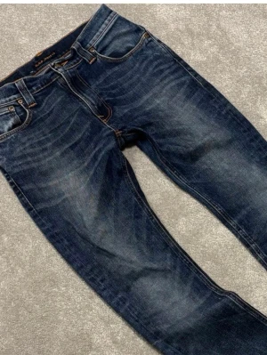 Mörkblå jeans från Nudie Jeans - Snygga mörkblå jeans från Nudie jeans. Skorna är slitna där nere och har ett hål vid grenen men man kan sy den lätt själv eller hos en skräddare för 50 kr. Jeansen sitter slim. hål i båda fram fickorna också men det syns inte och dem är små.