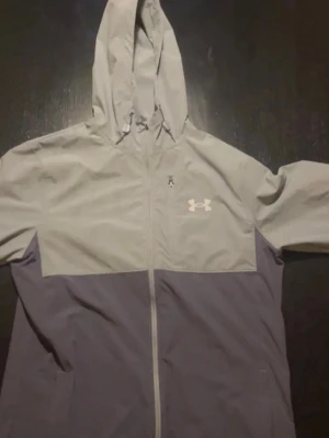 Grå Under Armour vindjacka - Snygg vindjacka från Under Armour knappt använd finns inga skador eller liknande pris kan diskuteras 