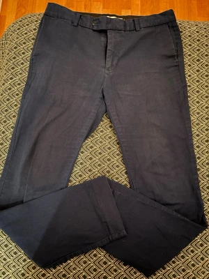 Mörkblå chinos med raka ben från PIER ONE - Snygga mörkblå chinos med klassisk passform och raka ben. Byxorna har bälteshällor, två sidofickor fram och två bakfickor med knapp. Perfekta för en stilren och avslappnad look.