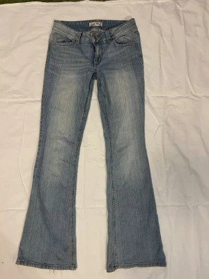 Ljusblå bootcut jeans från LEE - Säljer ett par ljusblå bootcut jeans från Lei med slitningar och broderade detaljer på bakfickorna. Jeansen har klassisk femficksmodell, låg midja och är tillverkade i denim med snygg tvätt. Perfekta för en avslappnad och trendig look. Nersydda i grenen så de har en liten slitning🥰