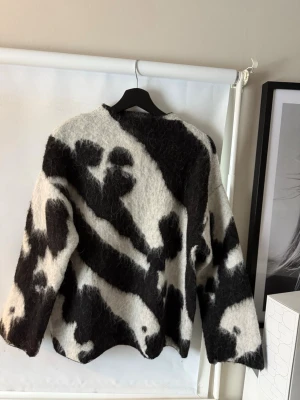Stickad tröja från STOCKH LM Studio - Säljer en fluffig stickad tröja från STOCKH LM Studio i storlek S. Tröjan har ett svartvitt  mönster, rund hals och raka ärmar. Materialet är mjukt och har en lite lurvig yta🥰den är bara använd 1 gång 