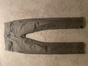 Dondup jeans - Snygga grå slim fit jeans med klassisk femficksdesign och dragkedjegylf. Jeansen har en något tvättad look och raka ben. Perfekta för en avslappnad och trendig stil. Lite slitna vid fickorna som man ser på bilderna men inget som påverkar användningen.