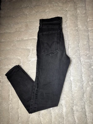 Levi's Mile High Super Skinny jeans - Snygga svarta Levi's Mile High Super Skinny jeans med hög midja och smal passform. Klassisk femficksdesign, diskreta sömmar och stretchigt jeanstyg som sitter tajt hela vägen ner. Perfekta för dig som gillar en stilren och modern look. 