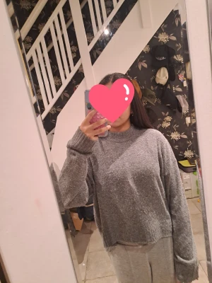 Grå stickad tröja från H&M XS - Mysig grå stickad tröja från H&M i storlek XS. Tröjan har en loose passform, ribbade muddar och är lite croppad med längre bakstycke. Perfekt för lager-på-lager och chill dagar. Enkel och stilren design som funkar till allt.