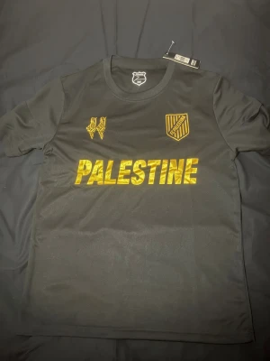 Palestine Fotbollsströja - Svart palestina fotbollsströja med guld-detaljer i storlek S men passar bra på M också. Helt ny och oanvänd 🙂