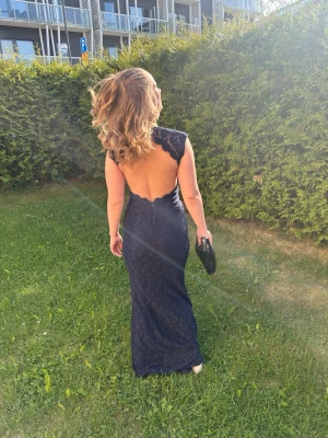 Marinblå spetsklänning med öppen rygg/ balklänning - Säljer en elegant marinblå långklänning med spets och v-ringad hals. Klänningen har en riktigt snygg öppen rygg. Jag hade den 2025 på balen och köpte den på Plick. Den är omsydd för att passa min kroppsform och längd. Jag är 158cm men har klackar på bilderna. Skriv vid fler frågor.