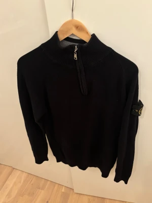 Svart stickad tröja från Stone Island - Svart stickad tröja från Stone Island med half zip och hög krage.. 