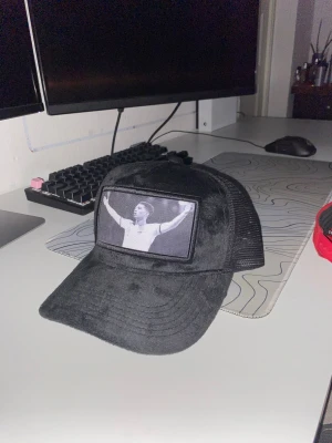 Svart manchesterväst från Evosportswear - Säljer en svart väst från Evosportswear i mjuk manchester med mesh på sidorna. Framsidan har ett stort svartvitt tryck med en person som firar. Västen har klassisk form och justerbar passning baktill. Perfekt för dig som gillar sportig stil.