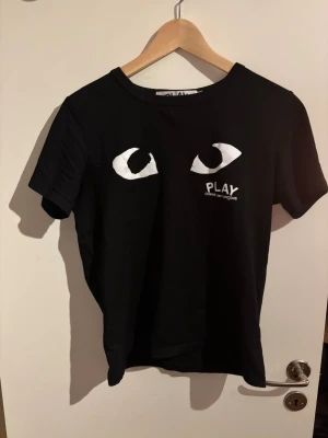 Svart Comme des Garçons Play t-shirt - Svart t-shirt från Comme des Garçons Play med ikoniska vita ögon-trycket på bröstet och logga. Väldigt fint skick och storleken är S, hör av er! 🤩