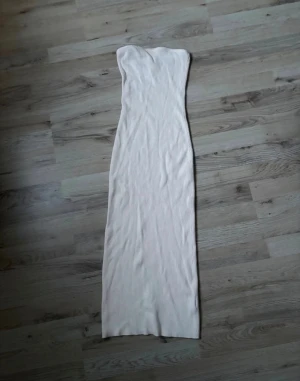Vit ribbad tubklänning från H&M - Säljer en lång, vit tubklänning från H&M i ribbad bomullsmix. Klänningen är axelbandslös och har en tight passform som framhäver siluetten. Perfekt för dig som gillar minimalistisk och stilren look.