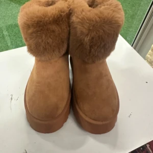Bruna boots med fuskpäls och platåsula 39/41 - Säljer 2 par bruna boots med fluffig fuskpäls runt skaftet och bred platåsula. Skorna har rund tå och är tillverkade i mockaimitation med dekorativt band bak. Perfekta för kalla dagar när du vill vara både varm och snygg.